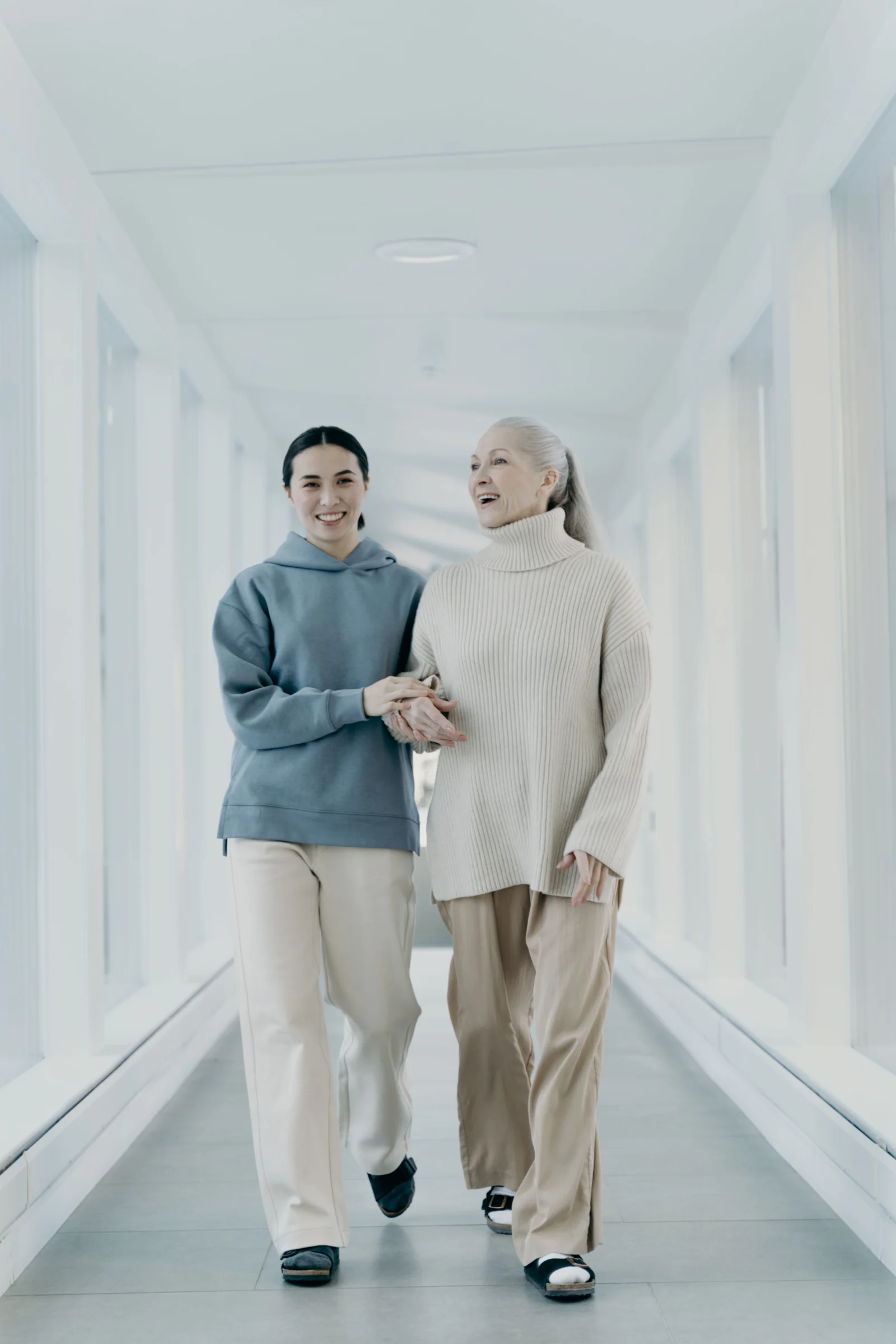 Older woman and younger companion walking together in a bright interior